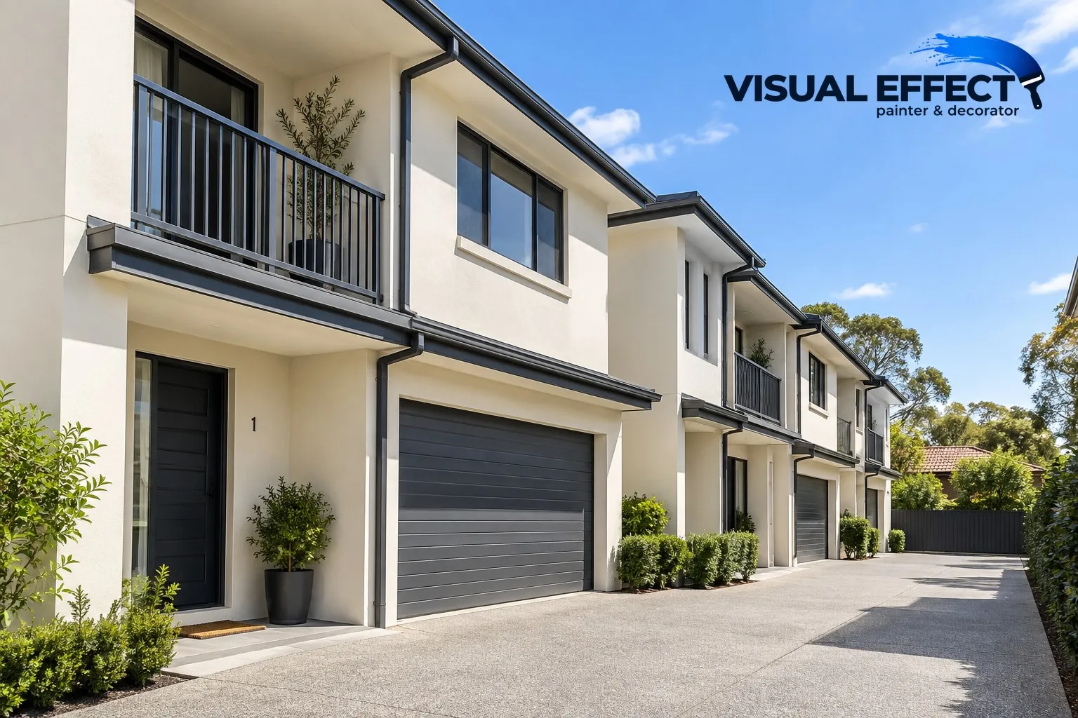 Row of cream rendered townhouses with charcoal trims and garage doors